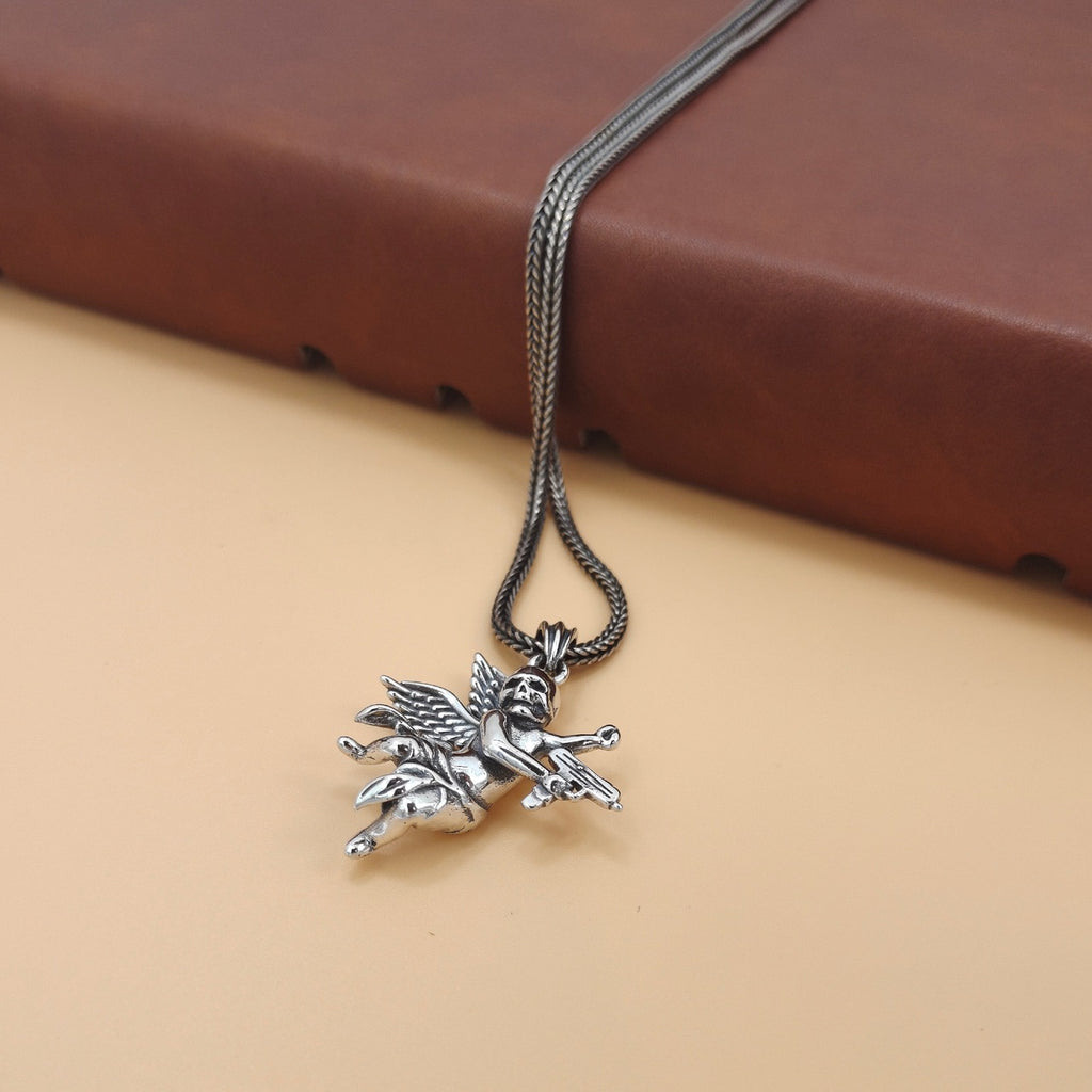 S925 sterling silver armed angel skull pendant close-up on tan surface showing dimensional wing feathers and skull features