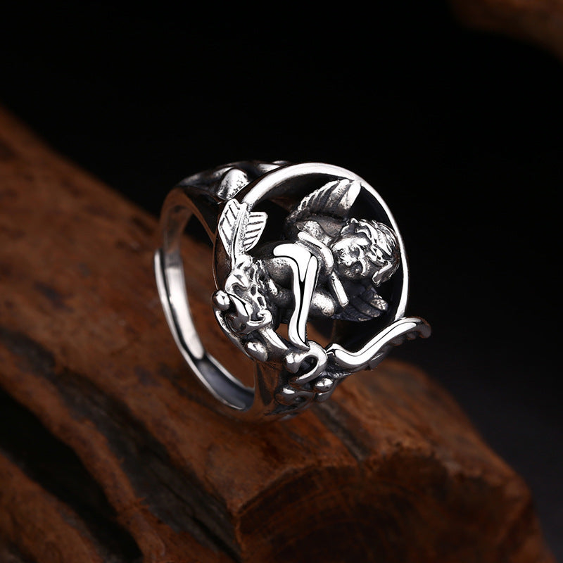 S925 sterling silver cupid ring angled on wood showing crescent moon setting, cherub sculpture and gothic romantic style