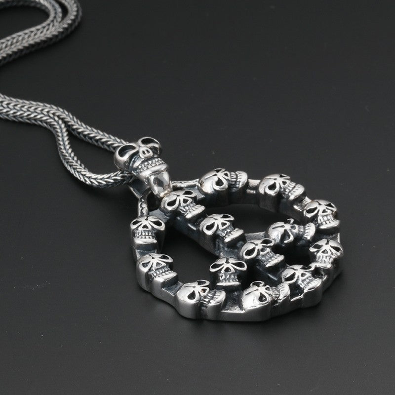 S925 sterling silver peace symbol skull pendant on dark surface showing intricate skull arrangement, oxidized accents and dimensional sculpting