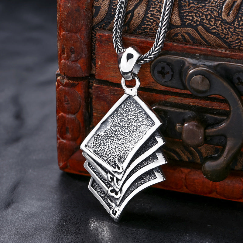 Back view of S925 sterling silver poker cards skull pendant on dark surface showing reverse side oxidized finish and solid construction