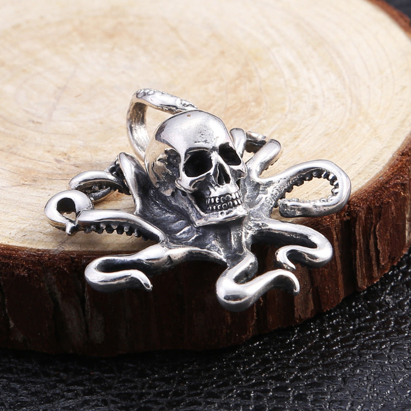 Close-up of the octopus skull pendant resting on cut wood, highlighting engraved textures and curled tentacles.