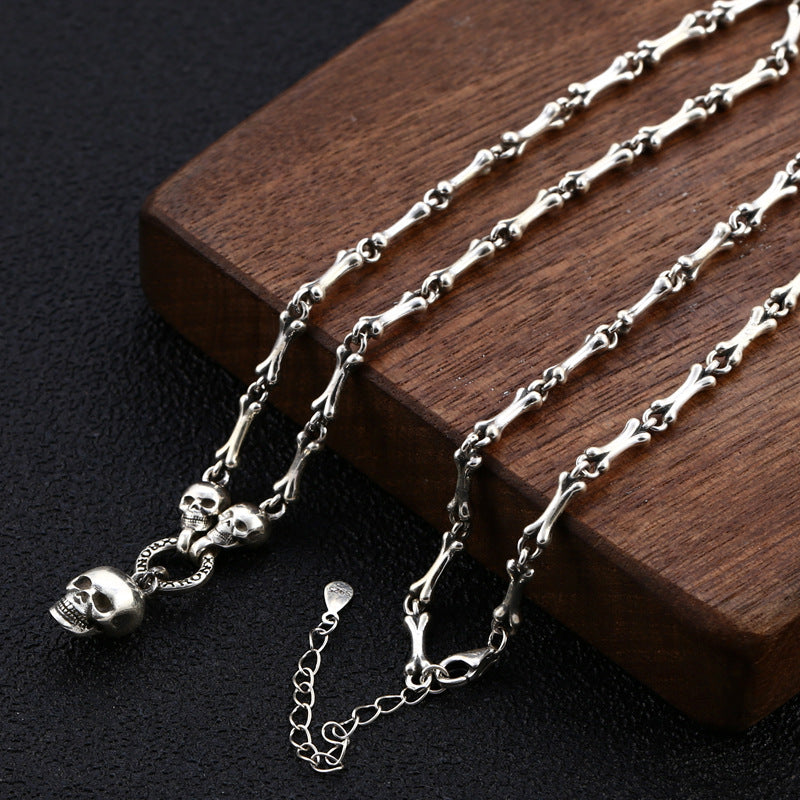 Close-up of S925 sterling silver skull bone chain on wood showing 3mm link detail lobster clasp and skull accents
