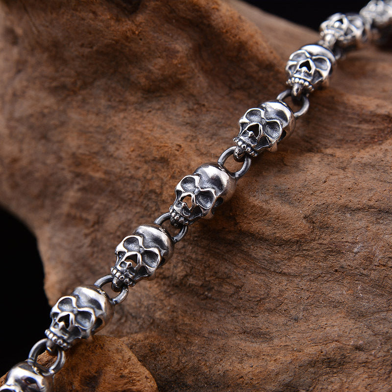 Close-up of S925 sterling silver skull chain necklace on wood showing 6mm bold skull link detail and oxidized finish