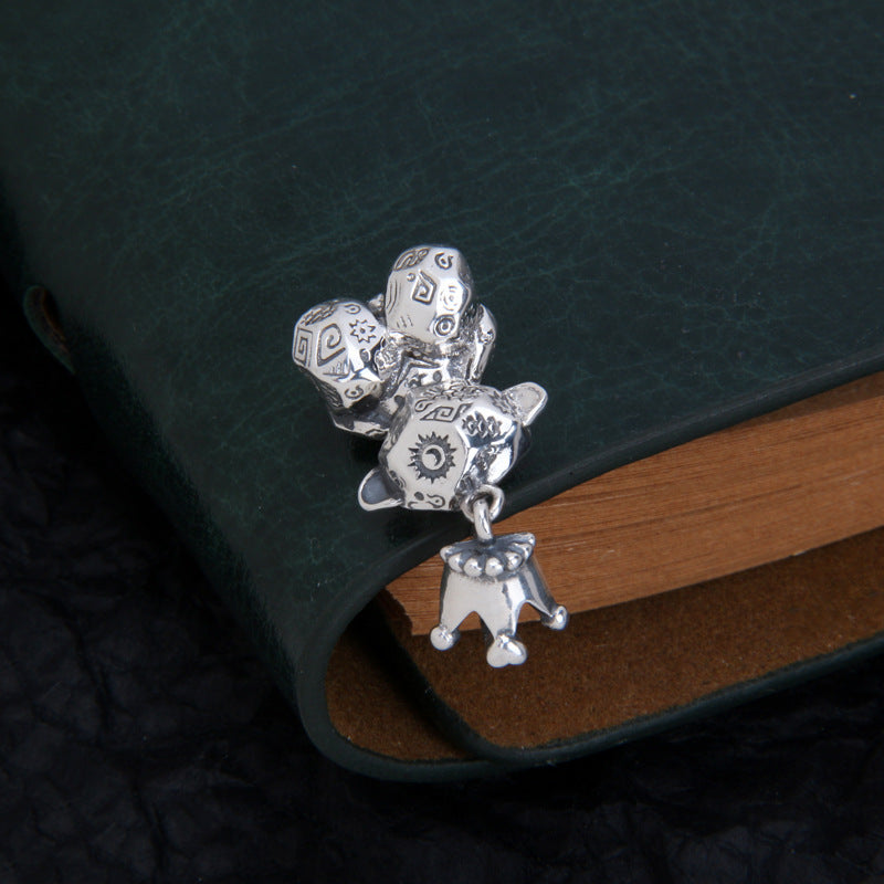 Overview angle of S925 sterling silver Thai bear charm on wood showing graffiti engraving pattern and solid construction