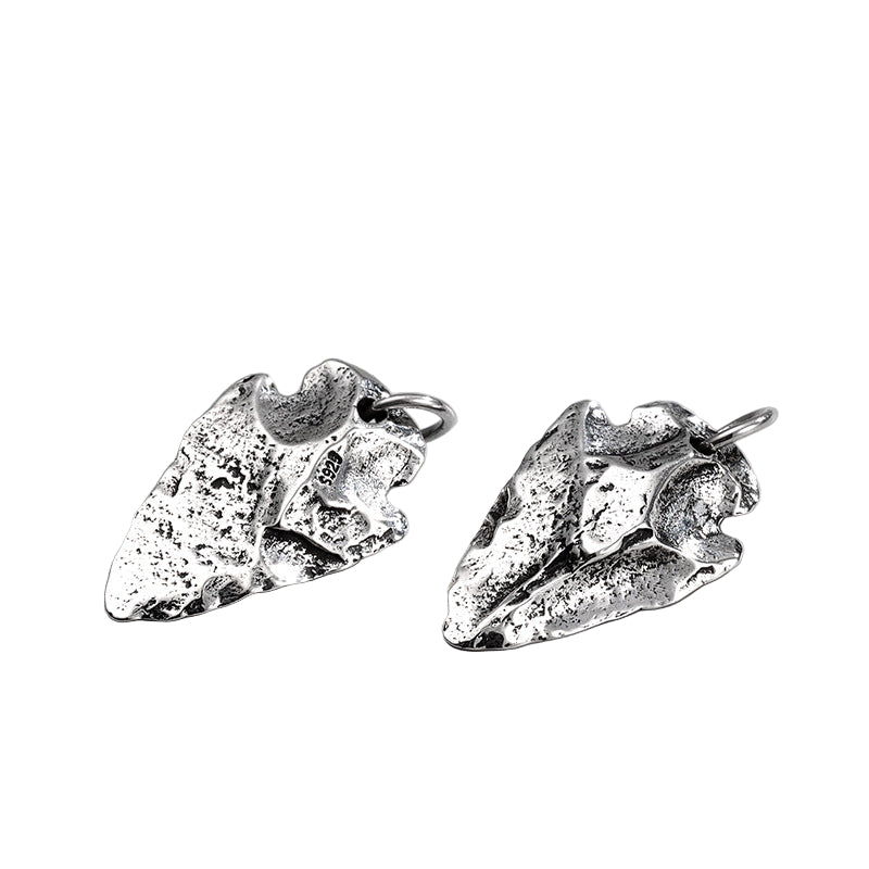 Front and back view of S925 sterling silver arrowhead pendant on light surface showing distressed textured surface and ancient warrior symbolism