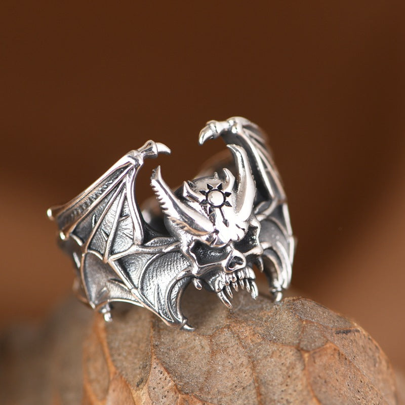 Angled view of S925 sterling silver bat skull ring on wood showing gothic bat skull spread wings and intricate craftsmanship