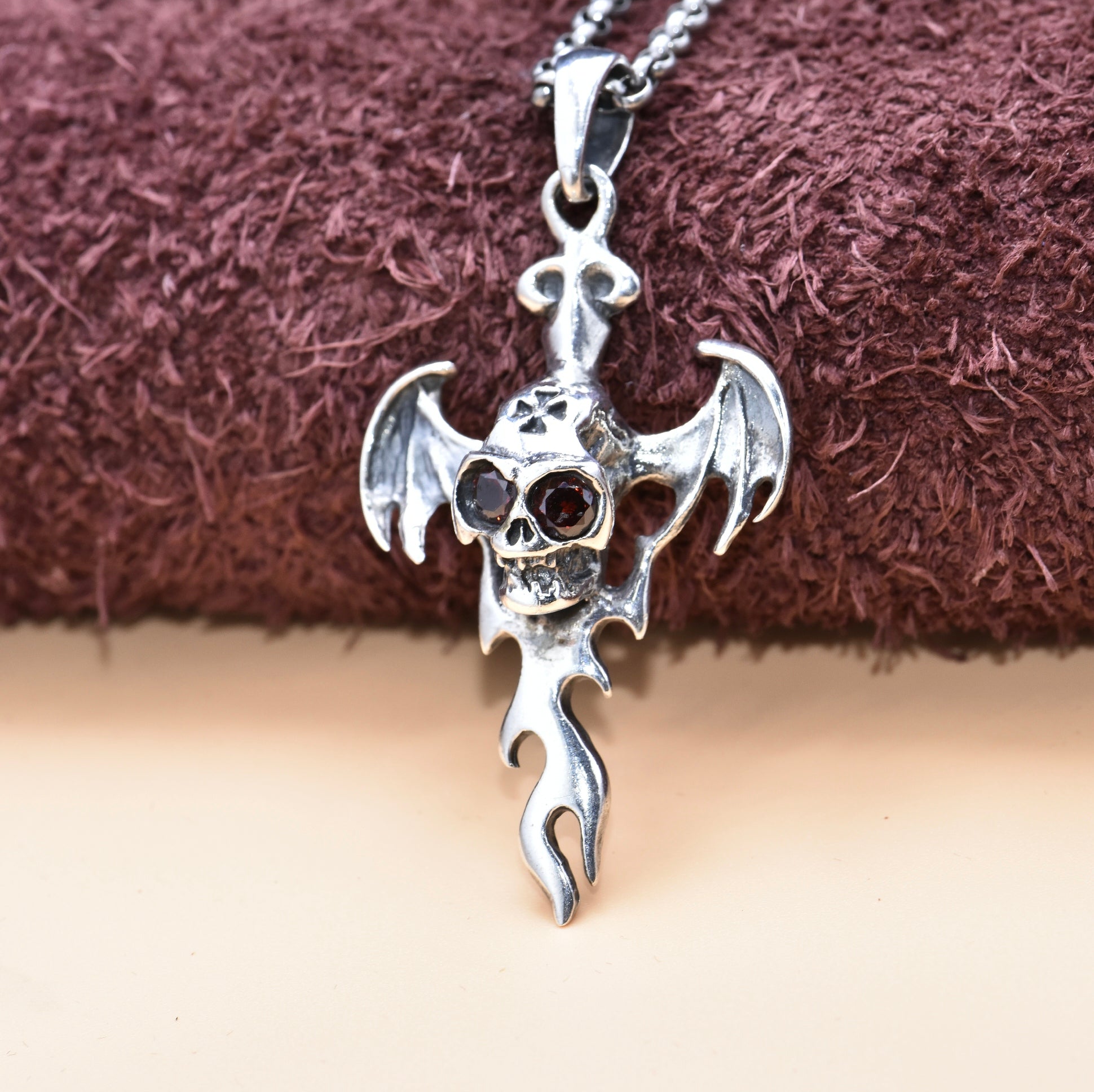 S925 sterling silver devil wing skull pendant with zircon eyes displayed on fabric showing gothic rebellious design