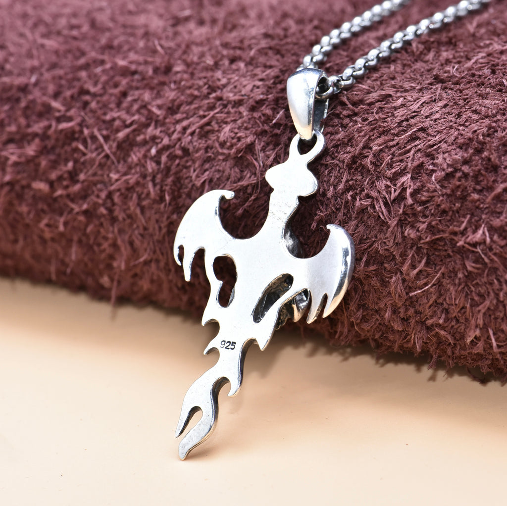 Back view of S925 sterling silver devil wing skull pendant on tan surface showing symmetrical wings and gothic craftsmanship