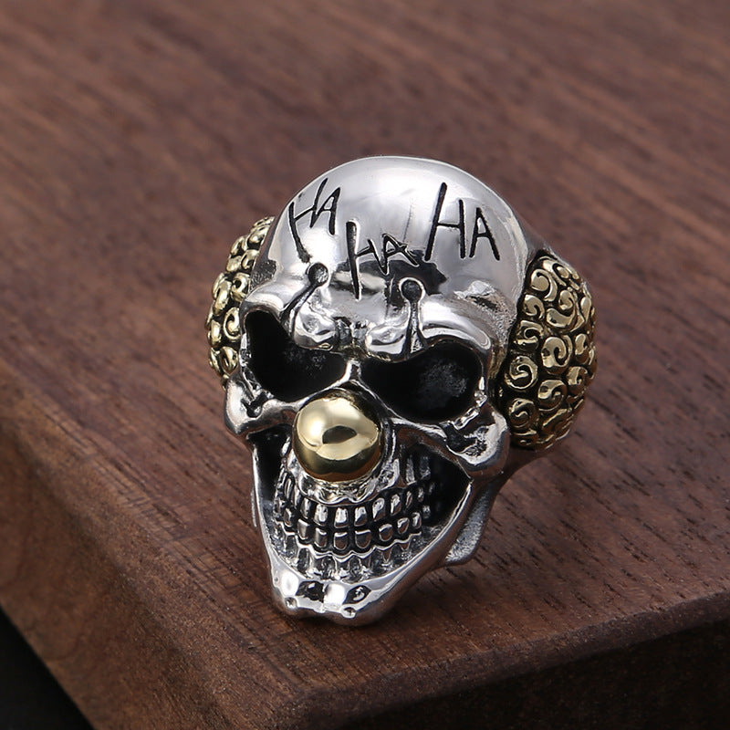 S925 sterling silver evil clown skull ring on dark surface showing dimensional teeth, oxidized finish and gold-tone accents