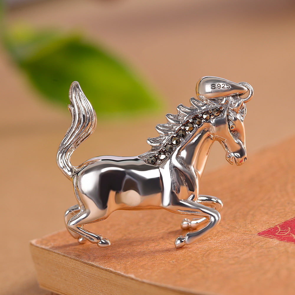 S925 sterling silver horse pendant on warm surface showing textured mane, polished body and dimensional sculpting