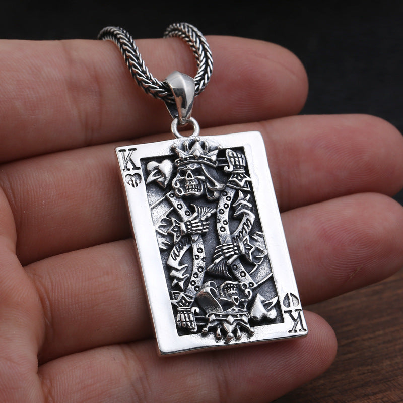 S925 sterling silver king card pendant held in hand showing dimensional skeleton detail, card border and oxidized crown elements