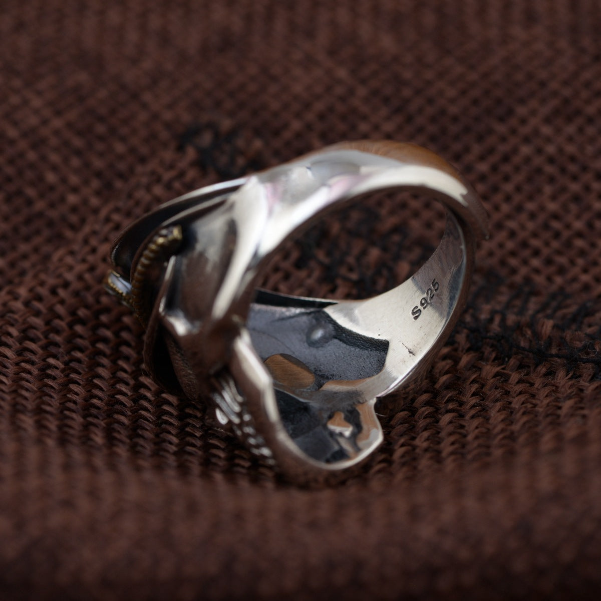 Top view of S925 sterling silver officer skull ring on wood showing adjustable open band construction and polished highlights