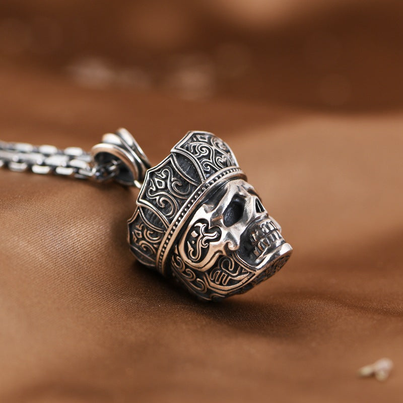 Decorative silver skull pendant on a brown fabric background