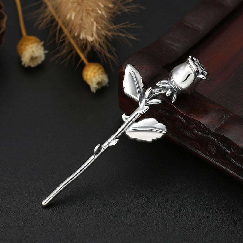 S925 sterling silver rose pendant on dark surface with dried flowers showing detailed petal design and romantic elegance