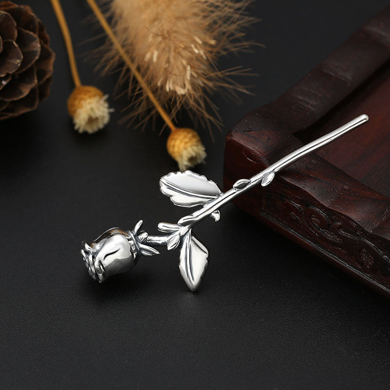 Vertical view of S925 sterling silver rose pendant on dark surface showing full stem detailed rose bloom and timeless elegance