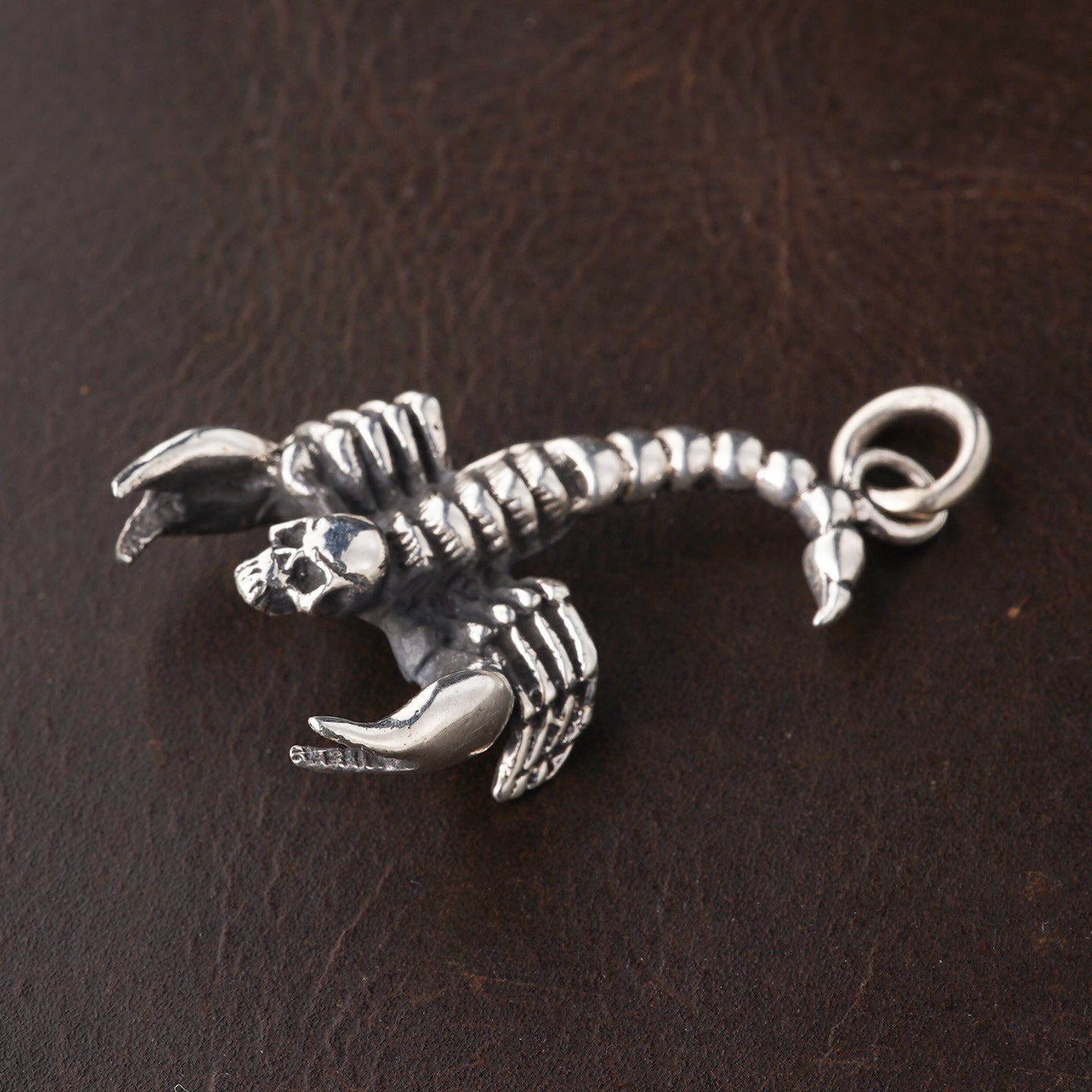Close-up of S925 sterling silver scorpion pendant on dark surface showing articulated segments skull detail and claw precision