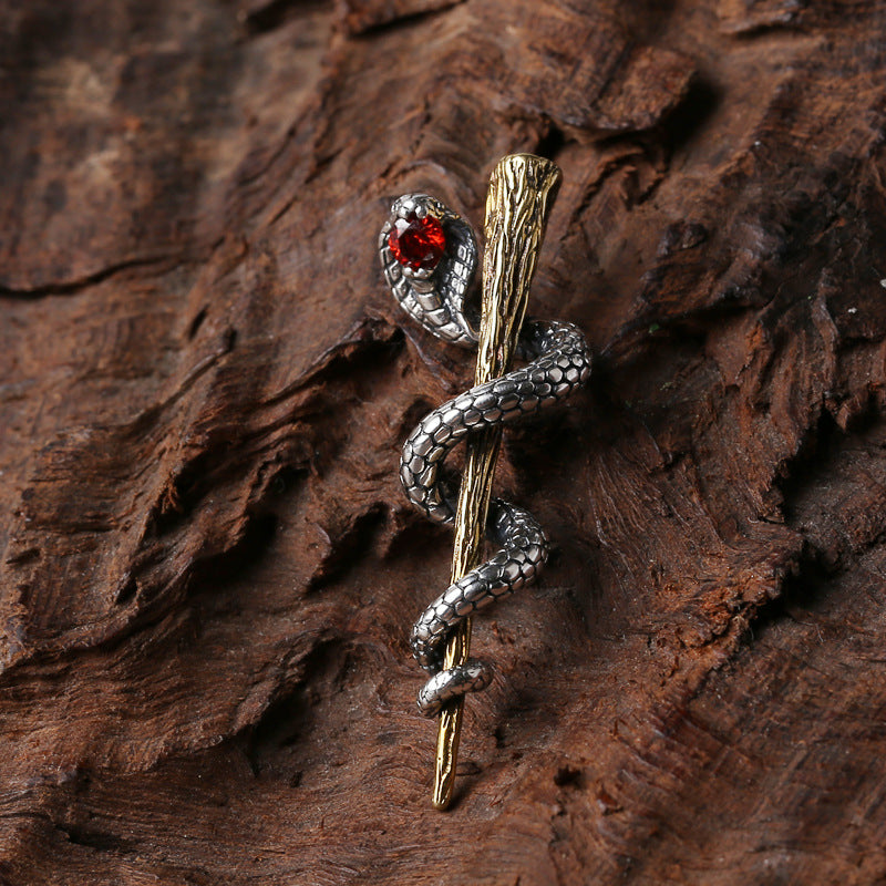 Close-up of S925 sterling silver serpent staff pendant on bark showing red zircon and oxidized vintage patina