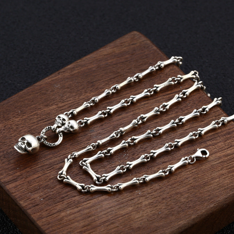 Full length view of S925 sterling silver skull bone chain necklace on wood showing adjustable 50-55cm gothic design