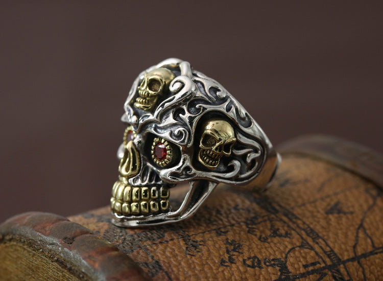 S925 sterling silver skull ring three-quarter view on wood showing dimensional sculpting, brass accents, and gothic design