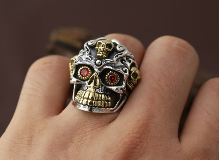 S925 sterling silver skull ring held in hand showing red zircon eyes, intricate crown work, and gothic detailing
