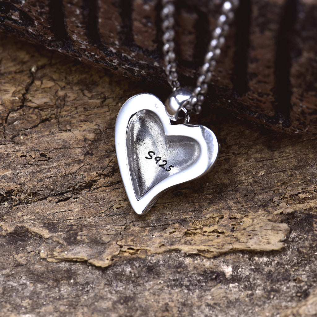 Sterling silver stitched broken heart pendant back view on wood surface showing S925 stamp and smooth finish