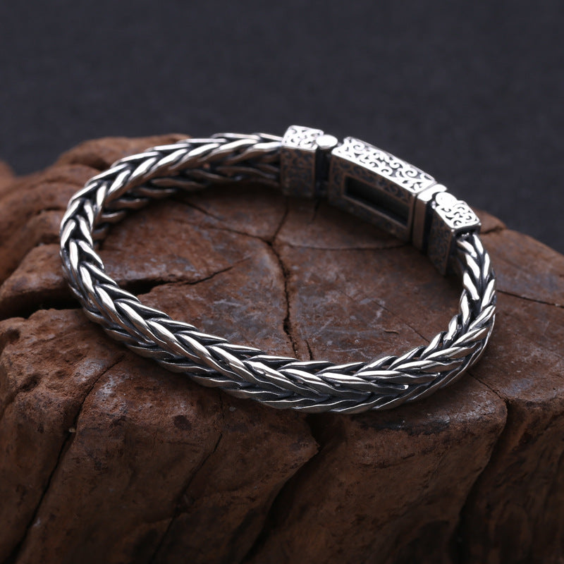S925 sterling silver wheat chain bracelet on dark surface showing dimensional weave, oxidized finish and secure clasp